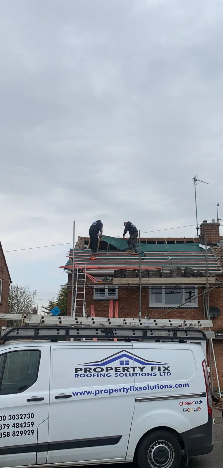 Roofers fitting a new roof membrane on a semi detached house