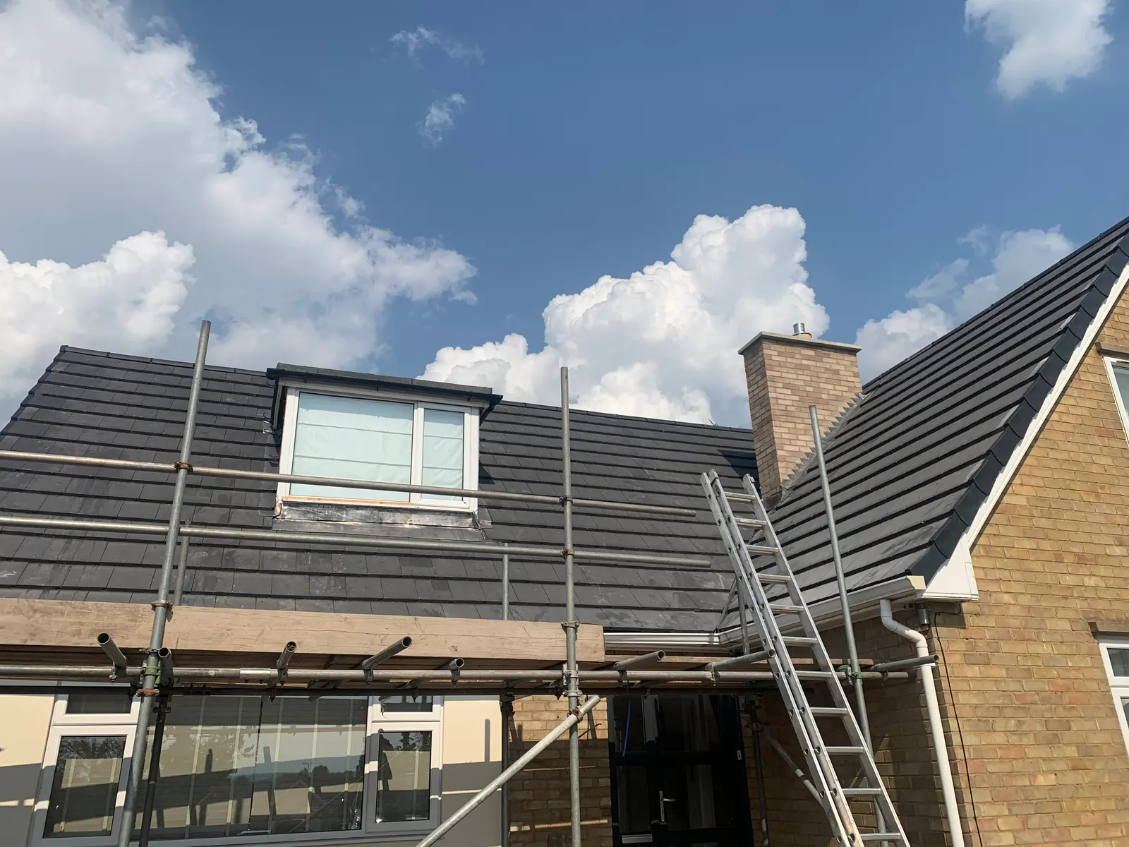 New grey tiled roof with a dormer and scaffolding